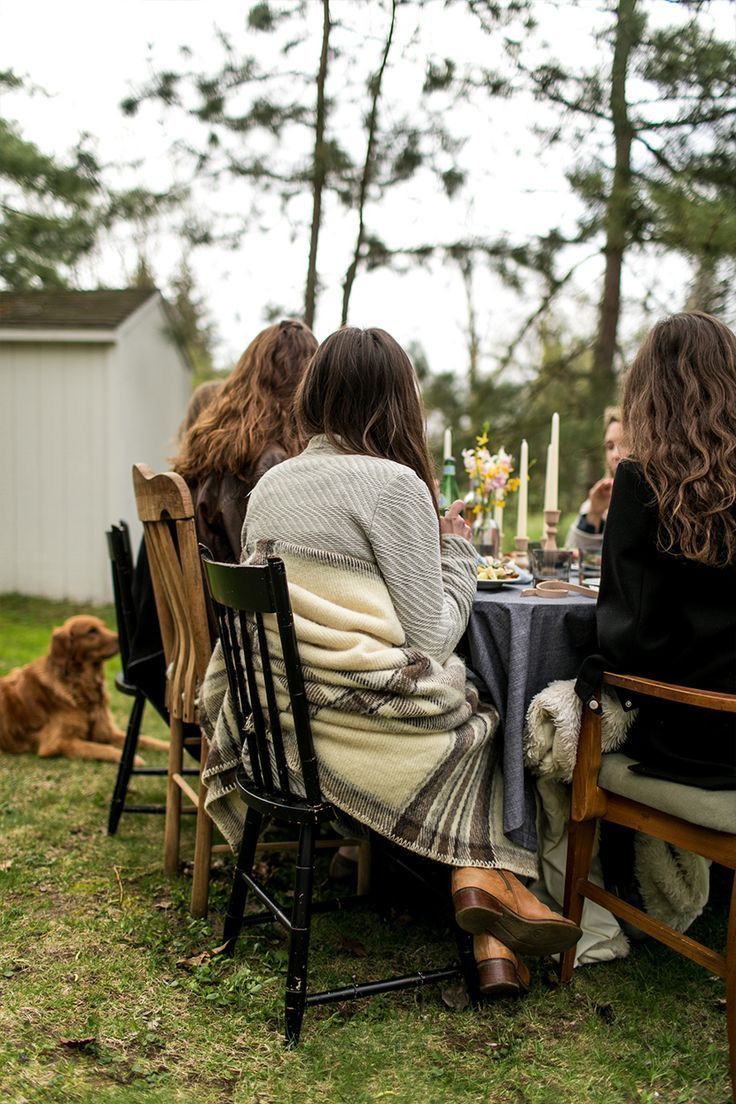 Friends seated outdoors at a table with candles