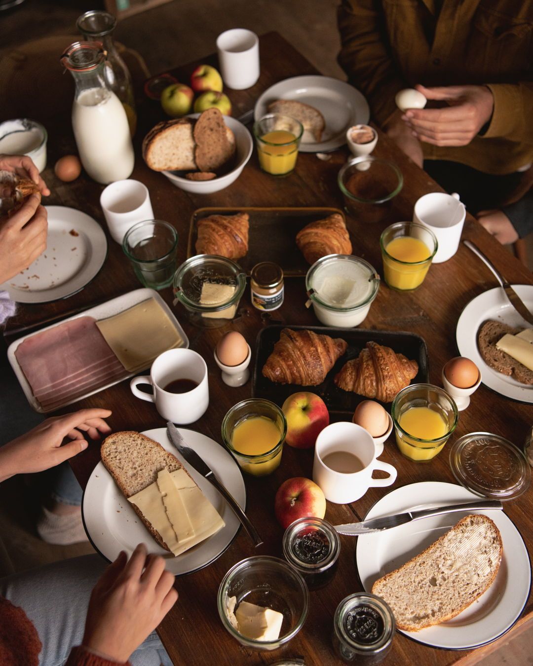 Breakfast spread with bread, croissants, eggs, juice and coffee